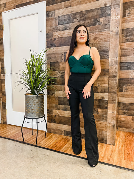 woman standing next to a small plant in front of a wooden wall