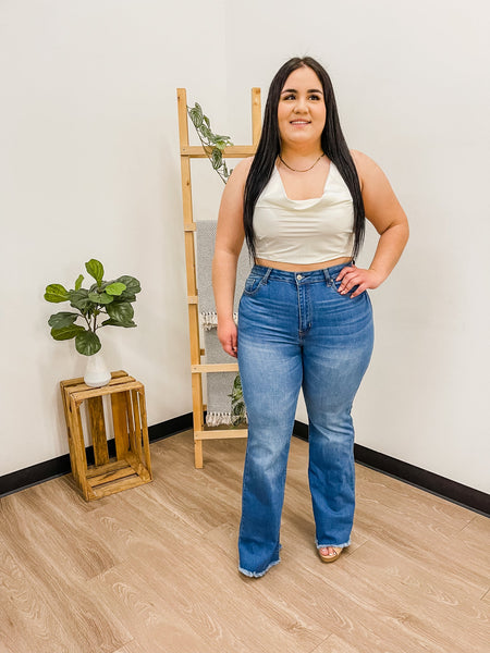 Model wearing white Lucia top with flared medium wash jeans. 