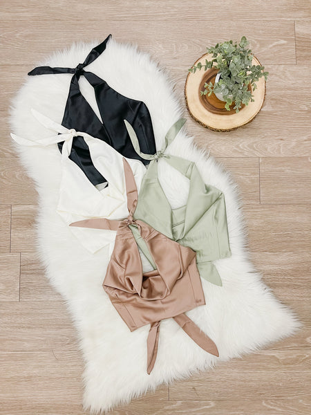 Flatlay image showing 4 colors of Lucia Top including black, white, sage and brown.