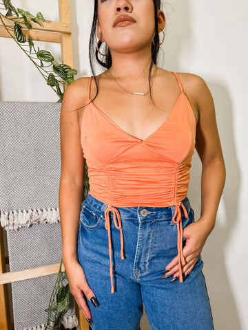 Close up image of woman wearing a sleeveless orange crop top