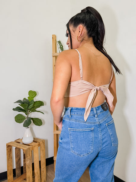 close up picture of woman wearing jeans and a tie back shirt