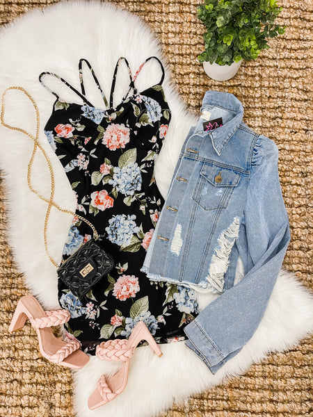 black floral dress with pink heels laid on faux rug with jean jacket folded next to it